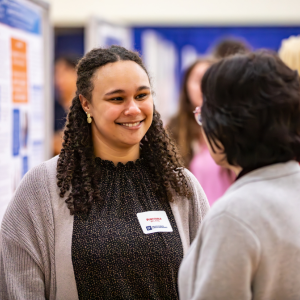 A researcher smiles at a person judging her poster