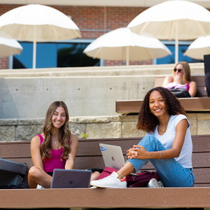 Two female UF students looking at camera and smiling outside UF Reitz Union